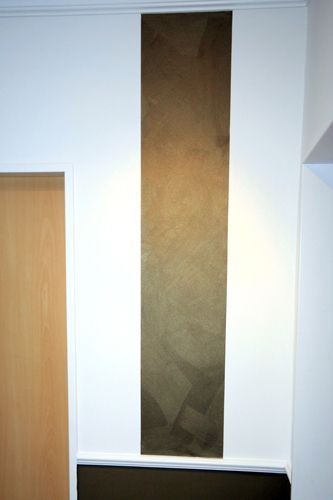 Eine weiße Wand mit einem braunen Streifen neben einer Holztür.