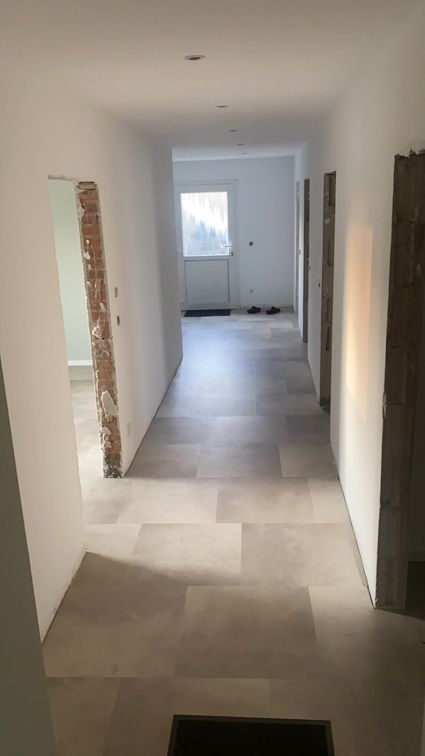 Ein langer Flur mit gefliestem Boden und einem Fenster.