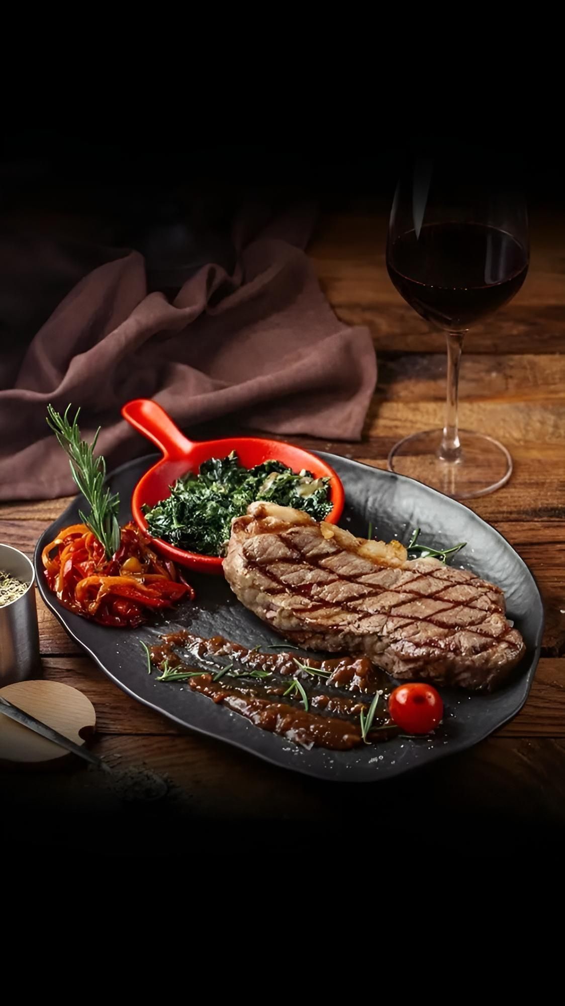 Gegrilltes Steak in Scheiben mit Rosmarin auf einer dunklen Holzoberfläche.