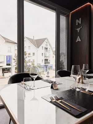 Gegrilltes Steak auf einer Schieferplatte, in Scheiben geschnitten und mit Rosmarin garniert auf einem dunklen Holztisch.