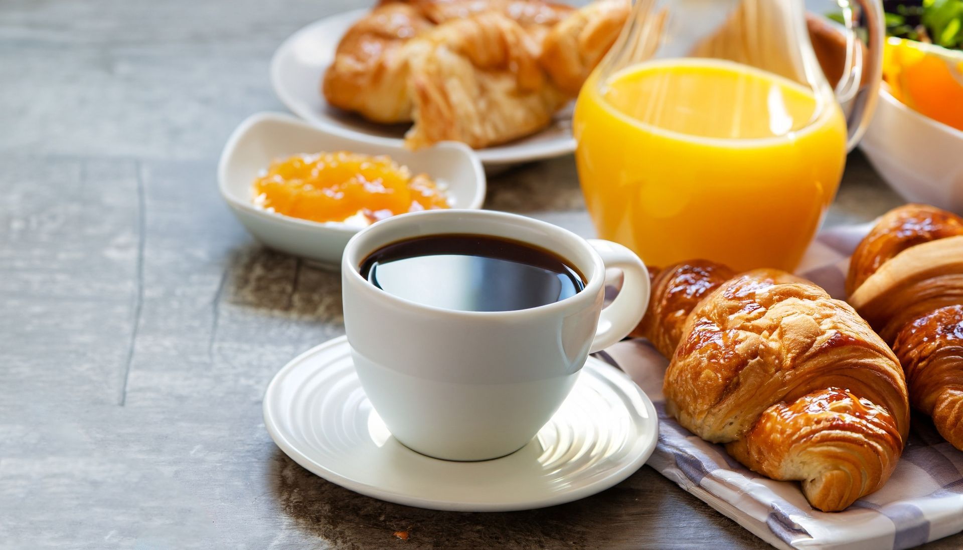 Café, jus d'orange et croissants sur une table de petit-déjeuner.