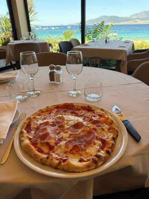 Une pizza sur une table du restaurant avec vue sur la mer.