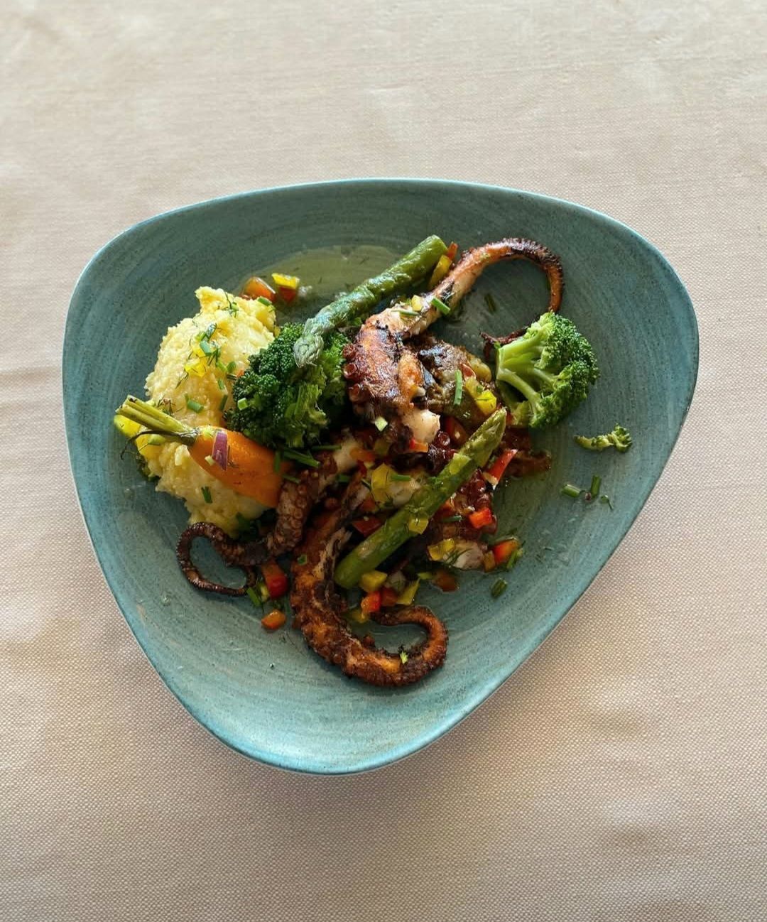 Poulpe grillé avec brocoli et riz sur une assiette turquoise.