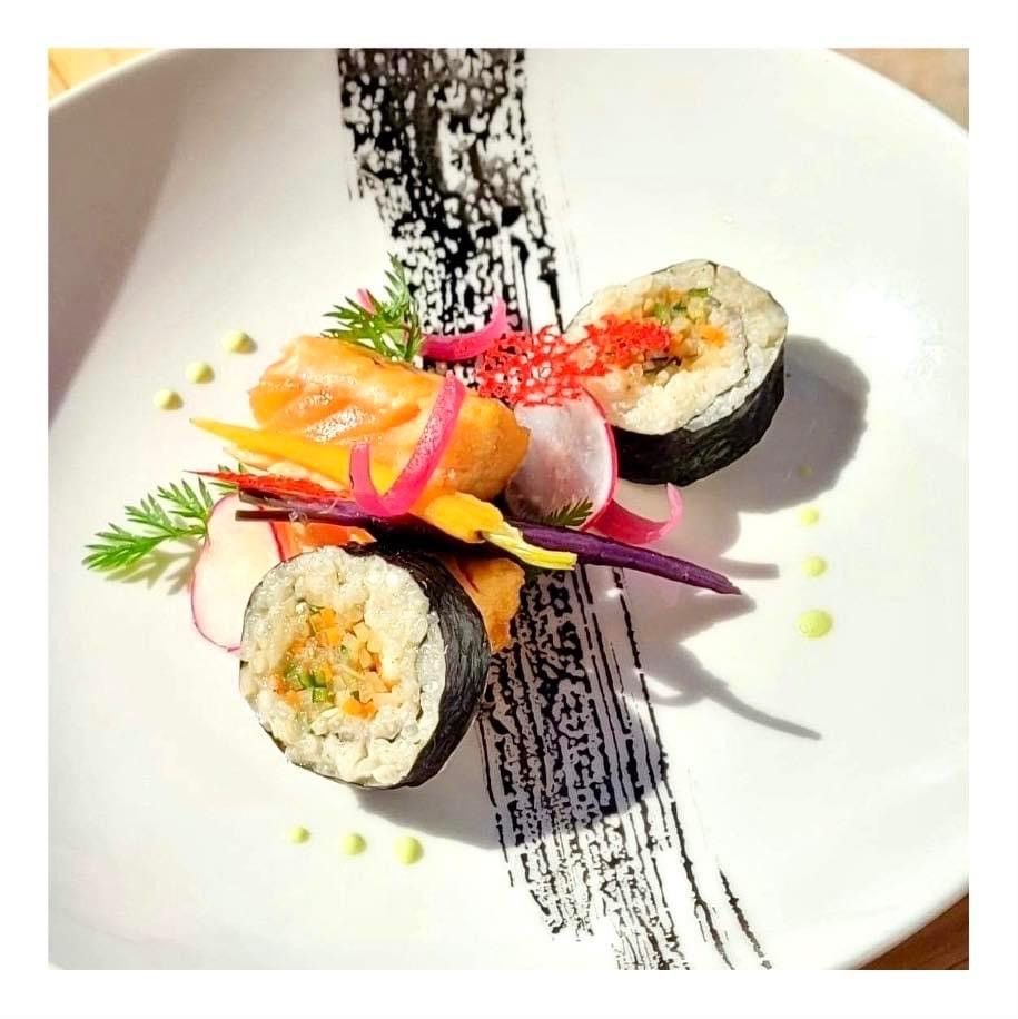 Rouleaux de sushi avec garniture colorée et sauce sur une assiette blanche.
