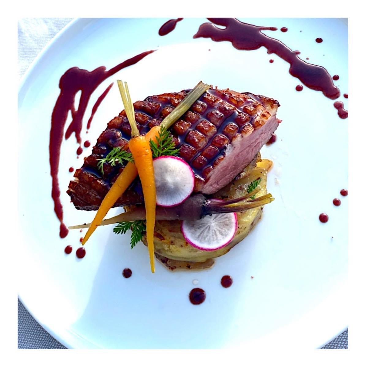 Viande poêlée avec légumes et radis sur une assiette blanche, arrosée d'une sauce brune.