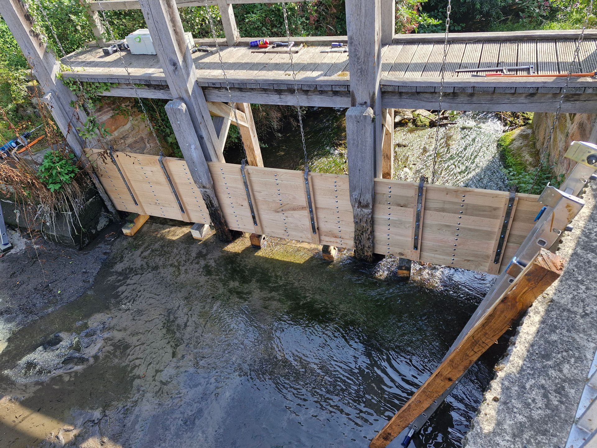 Pergola im Bau; Holzbalken und Stützen im Hinterhof mit Leitern und Werkzeugen.