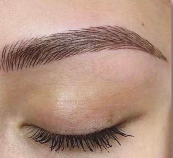 Primer plano del ojo cerrado de una persona, con cejas de color marrón oscuro, perfectamente delineadas y pestañas largas y oscuras.