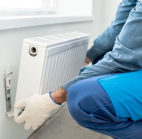 Un hombre está instalando un radiador en una pared.