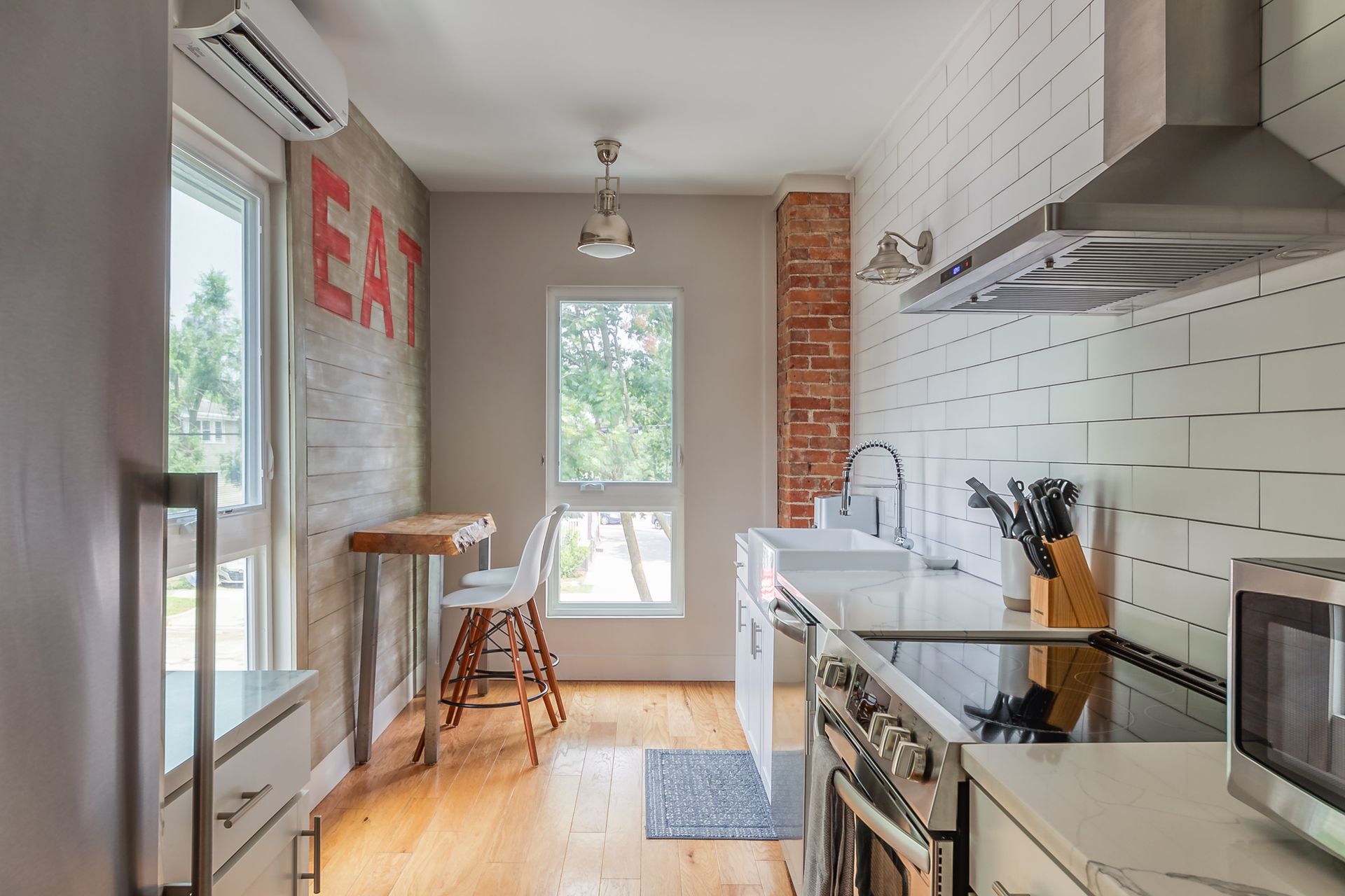 Modern kitchen with white counters, subway tile, and a small eat-in area with