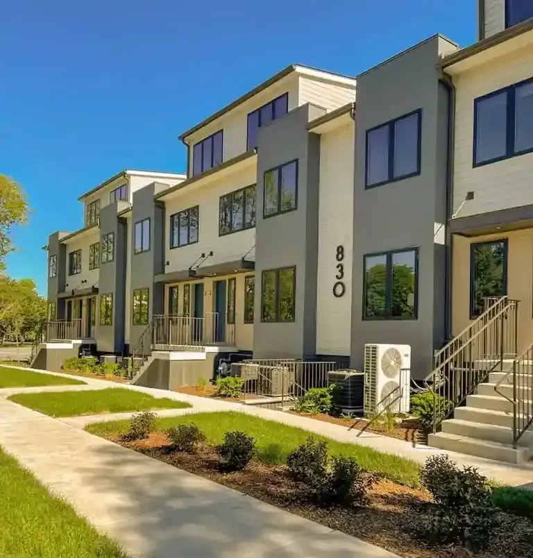 Row of modern townhouses with gray and white exterior, 830 visible. Blue sky and sidewalk in front.