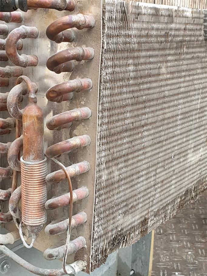 Eine Nahaufnahme einer schmutzigen Kupferspule an einer Wand.