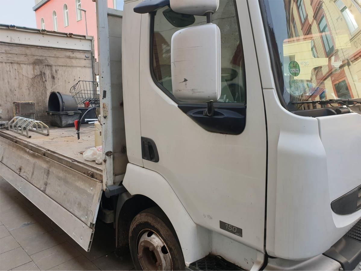 Ein weißer Lastwagen steht vor einem Gebäude.