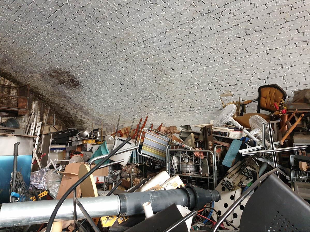 Ein Haufen Schrott in einer Garage mit einer Backsteinmauer im Hintergrund.