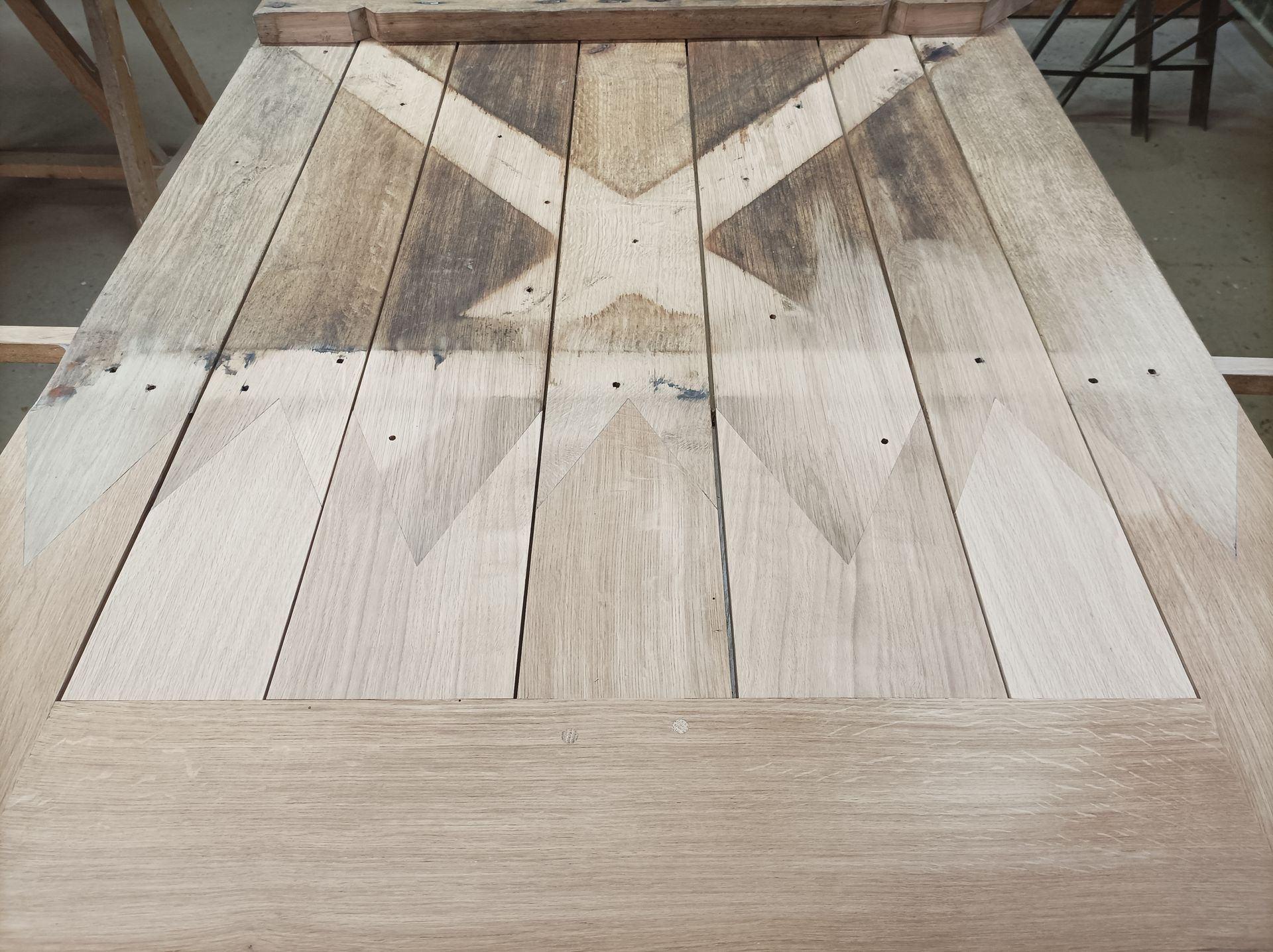 Table en bois avec motif décoratif en forme de X, en bois clair sur fond de bois foncé, non finie.