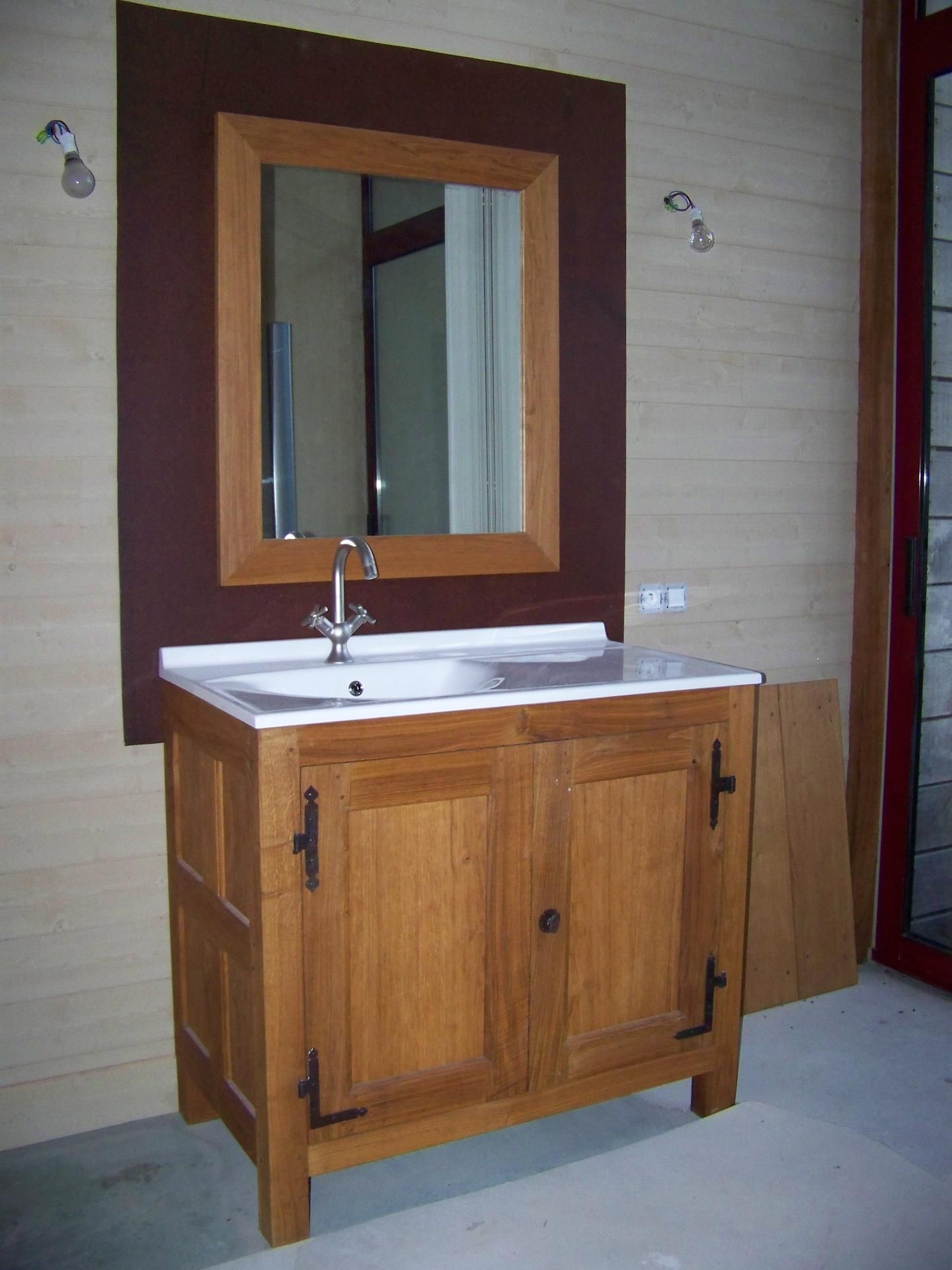 Meuble-lavabo en bois avec lavabo, miroir et deux portes. Tons bruns et beiges.