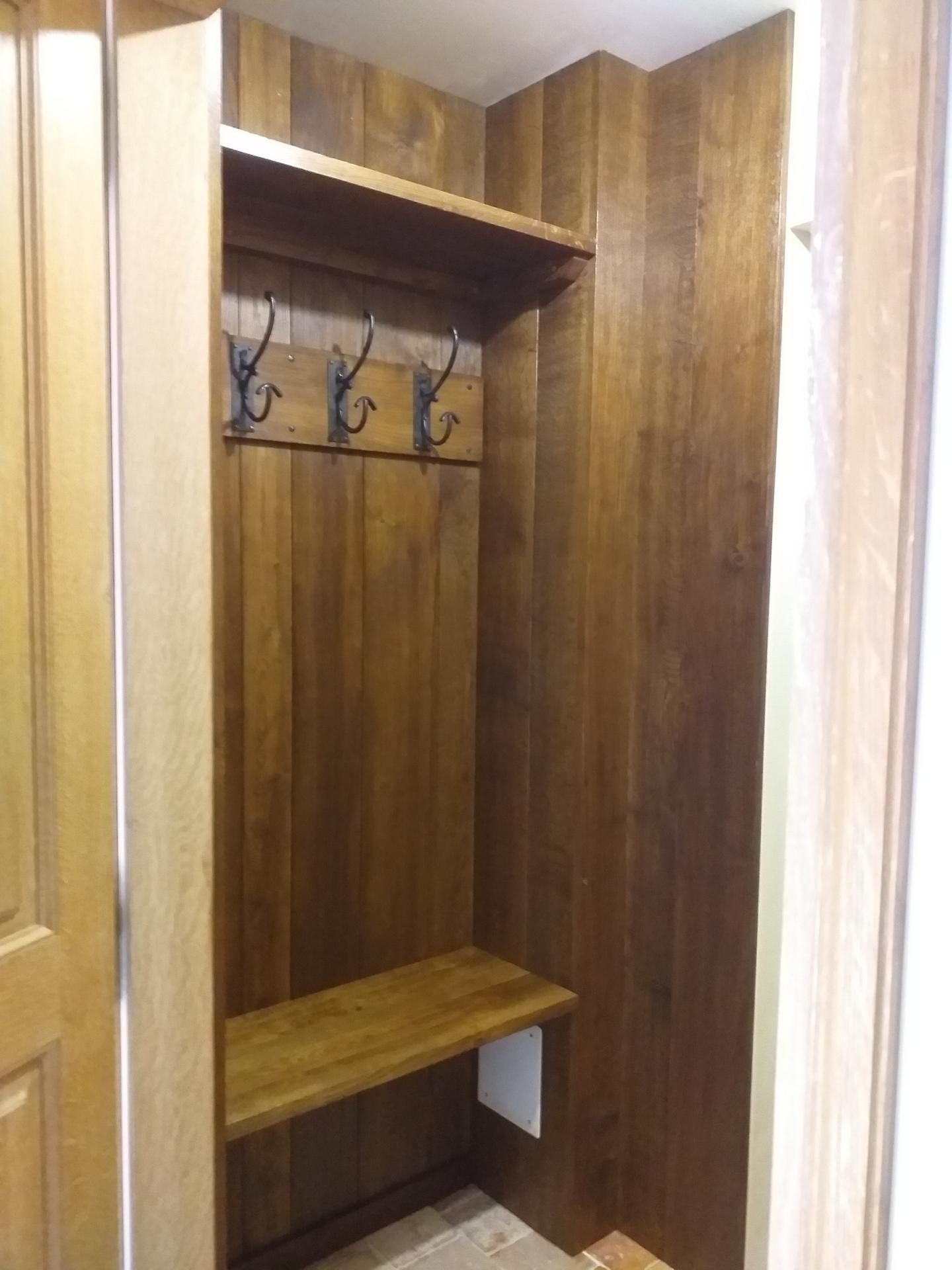 Entrée en bois avec crochets, étagère et banc.