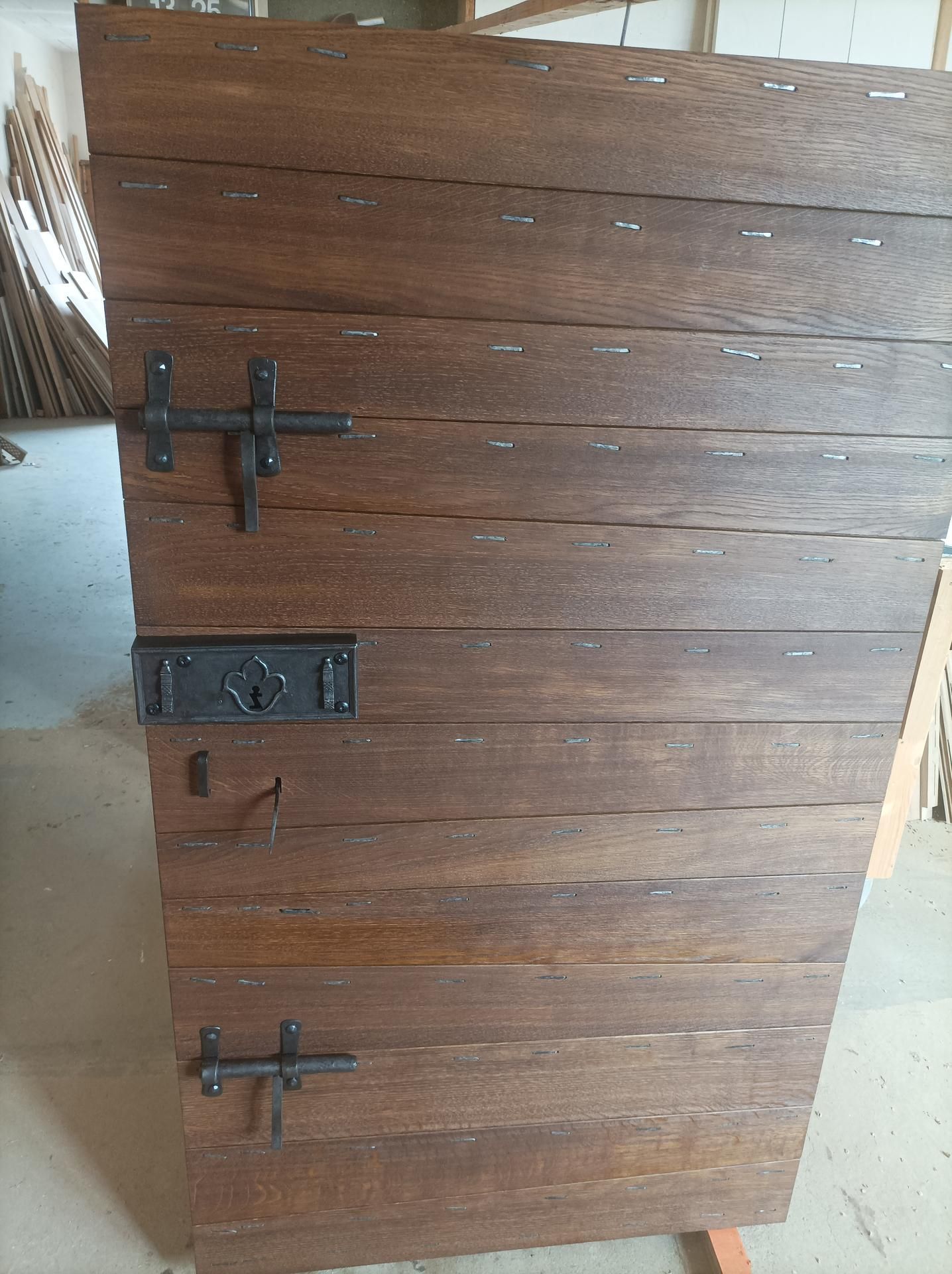 Porte en bois à planches horizontales, brun foncé, avec quincaillerie noire.