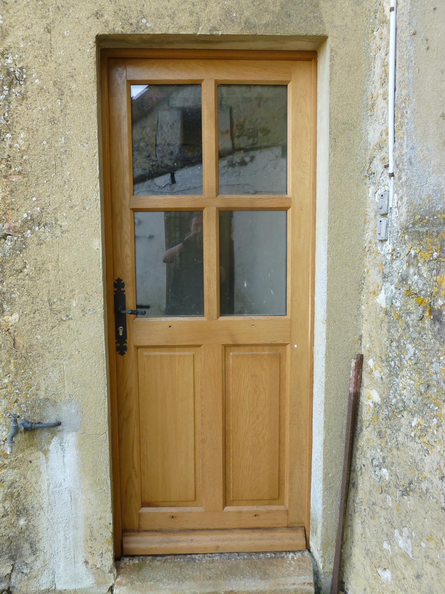 Porte en bois avec panneaux de verre encastrée dans un mur en pierre.