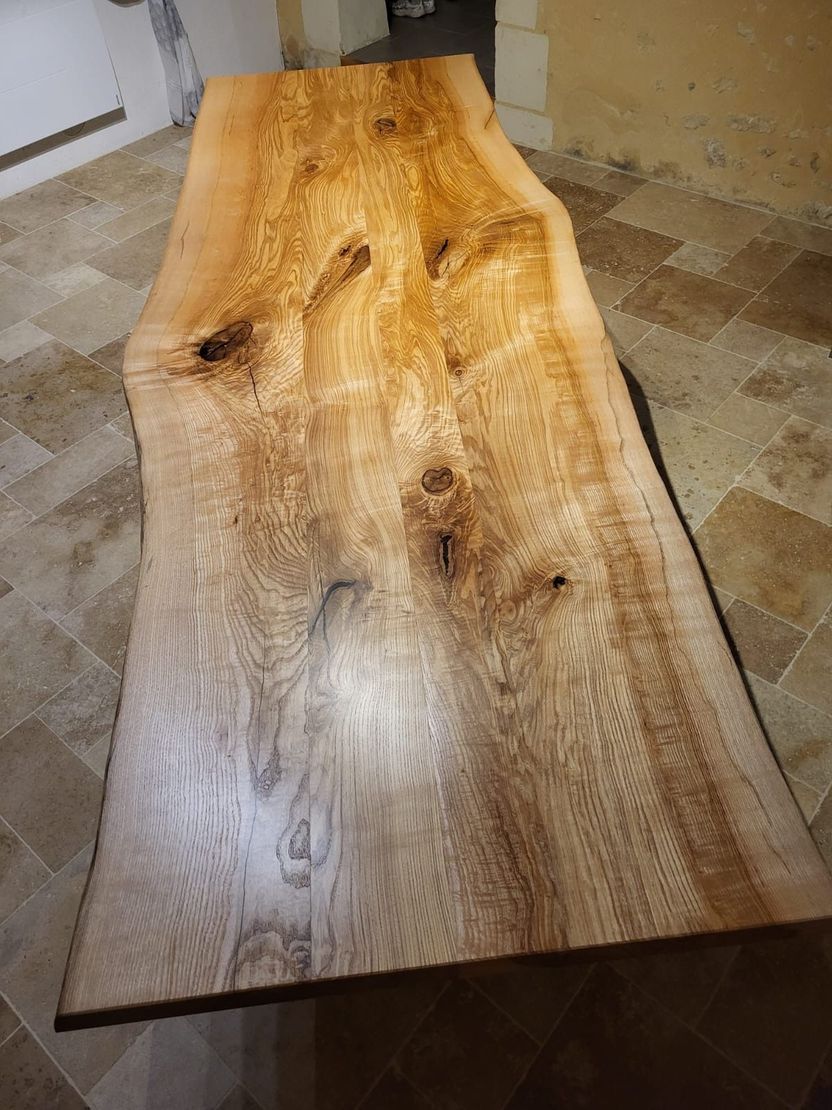 Table en bois massif avec bord naturel, veinage clair et foncé.
