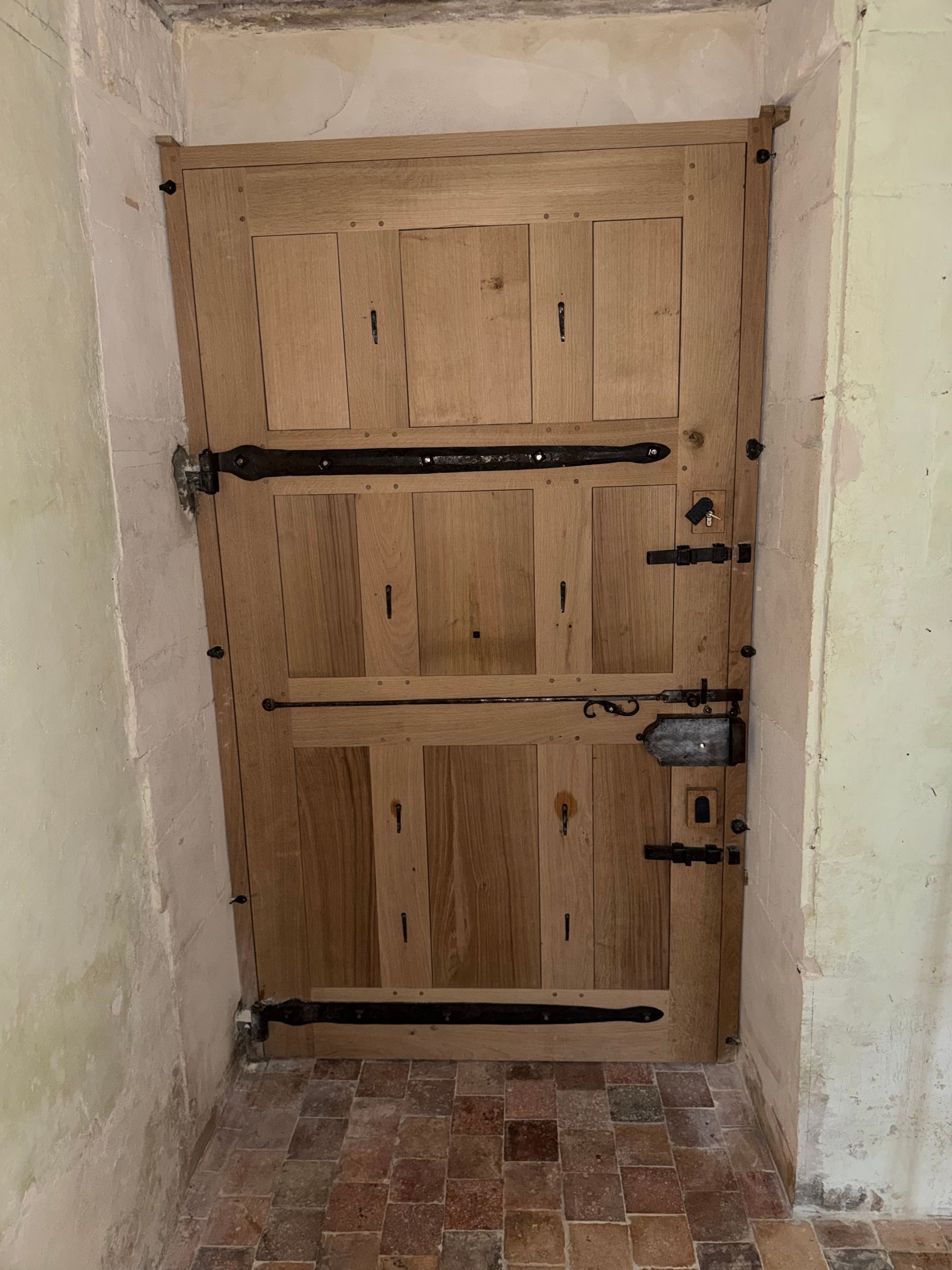 Porte en bois à panneaux blancs et bruns, sur des marches en pierre.