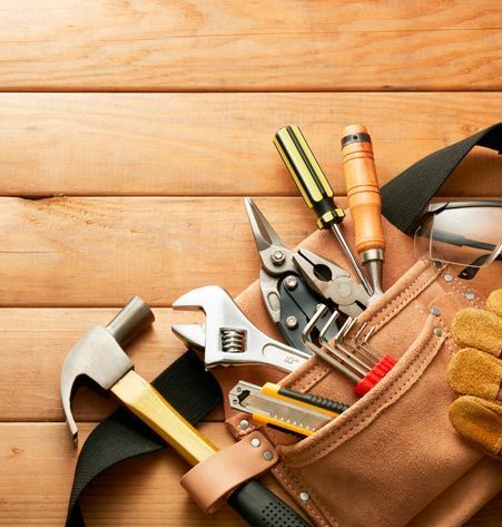 Un cinturón de herramientas lleno de herramientas y guantes sobre una mesa de madera.