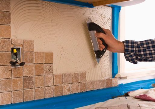 Una persona está colocando baldosas en una pared con una paleta.