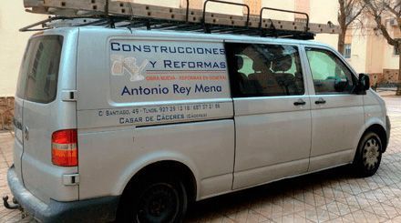 Una camioneta con una escalera encima está estacionada frente a un edificio.