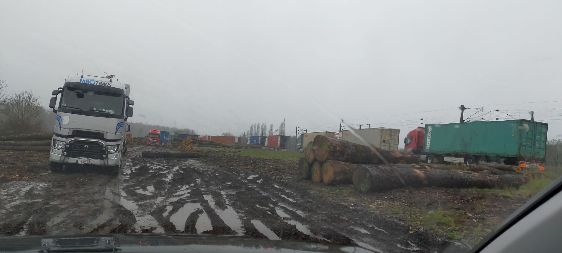 Camion sur un terrain boueux près d'une scierie par temps couvert.