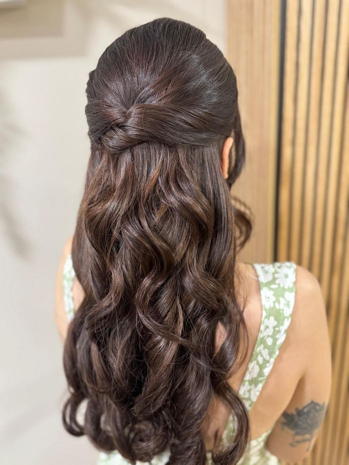 Mujer con cabello oscuro y ondulado con un peinado mitad recogido y mitad suelto, con un vestido floral.