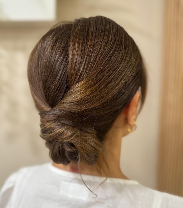 Mujer con cabello castaño peinado en un elegante recogido, visto desde atrás.