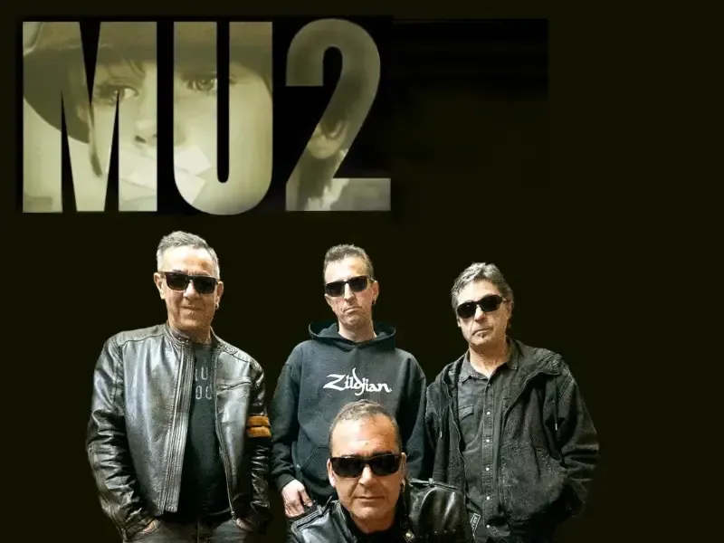 Miembros de la banda MU2 con gafas de sol y chaquetas oscuras posando sobre un fondo negro.