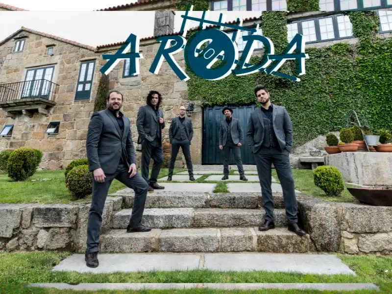 Cinco personas de pie sobre escalones de piedra frente a un edificio cubierto de enredaderas con el logotipo de ARODA encima.