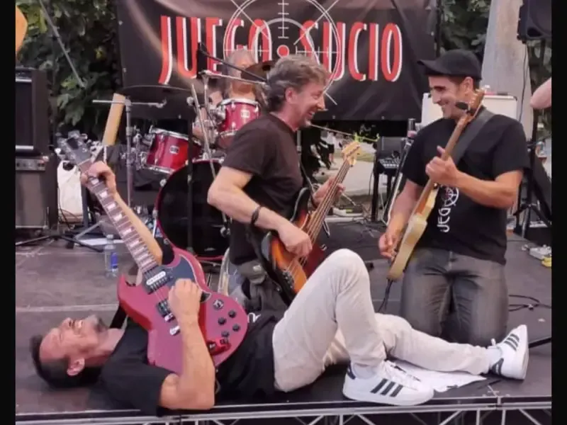 Tres músicos actúan en el escenario, uno de ellos tumbado tocando la guitarra delante.