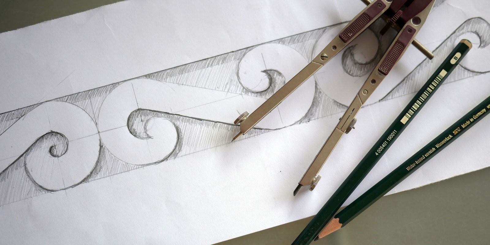 Zwei Staedtler Bleistifte und ein Zirkel auf einem Blatt Papier