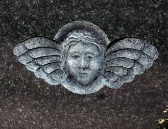 Eine Nahaufnahme einer Engelsstatue mit Flügeln auf einem Grab.