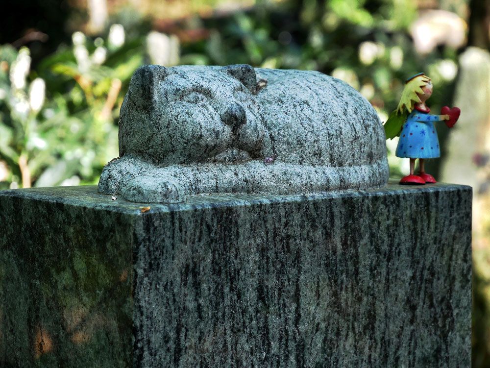 Eine Figur eines Mädchens, das neben einer Katzenstatue steht