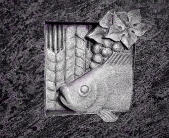 Eine Skulptur eines Fisches, Trauben und Weizen auf einer violetten Oberfläche.