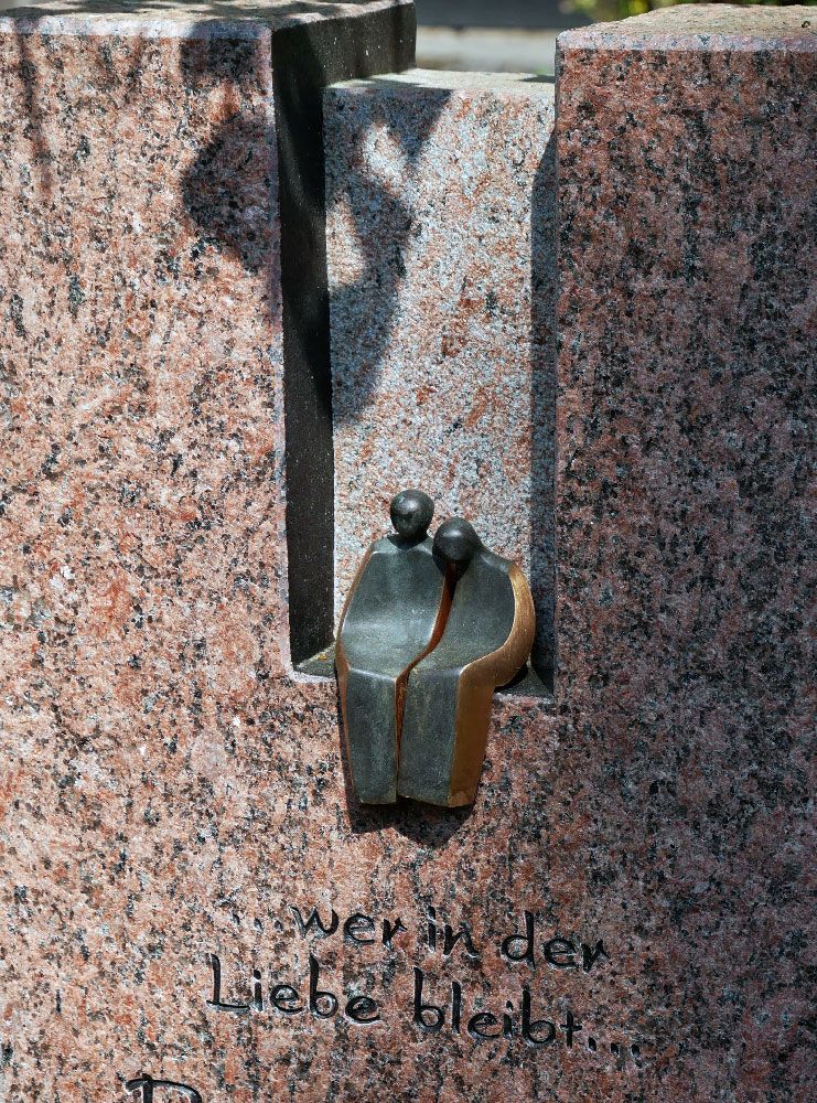 Eine Statue von zwei Menschen, die nebeneinander auf einer Granitwand sitzen