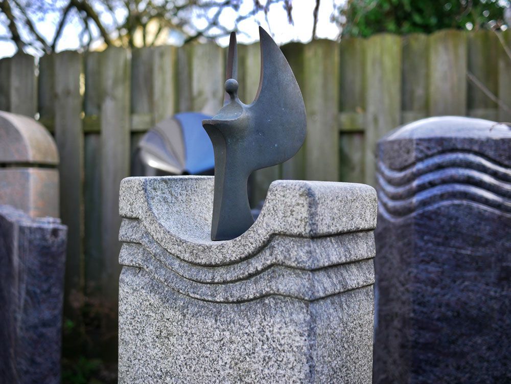 Eine Vogelstatue auf einem Felsen vor einem Holzzaun