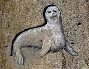 In eine Betonwand ist ein Siegel eingeritzt.