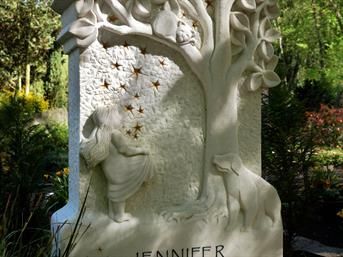 Eine Statue einer Frau, die unter einem Baum auf einem Friedhof steht.