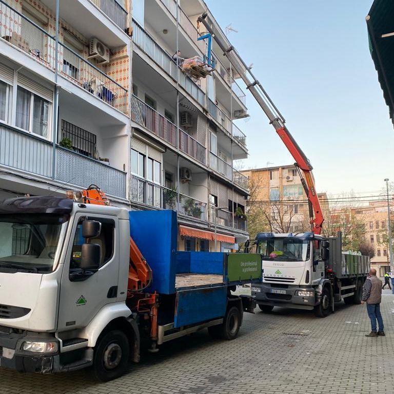 Un camión con una grúa acoplada está estacionado frente a un edificio.