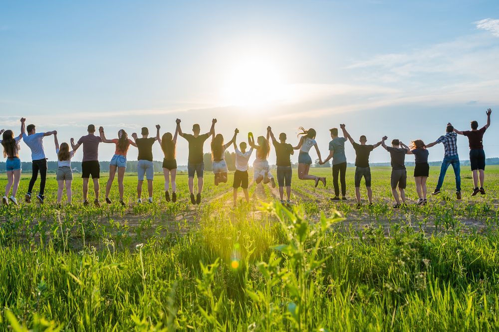 Un grupo de personas están de pie en un campo tomadas de la mano.