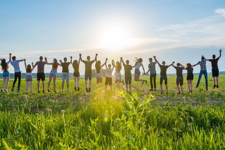 Un grupo de personas están de pie en un campo tomadas de la mano.