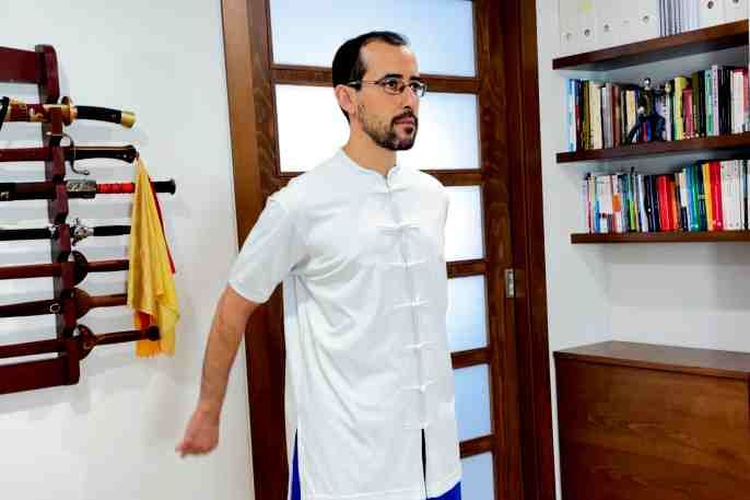 Un hombre con una camisa blanca está de pie en una habitación.