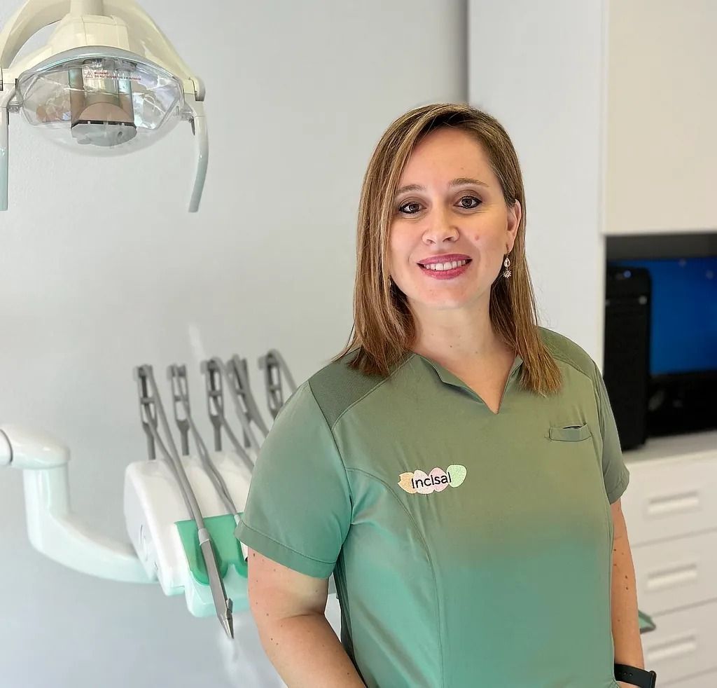 Una mujer con una camisa verde está de pie en un consultorio dental.