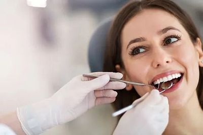 Una mujer está siendo examinada por un dentista.