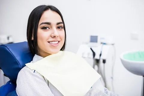 Una mujer sonríe mientras está sentada en una silla dental.