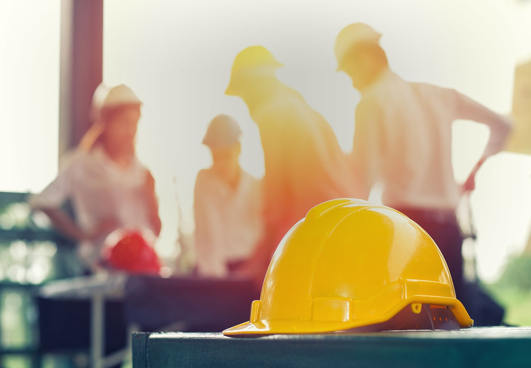 Casque de chantier au premier plan devant une équipe du BTP