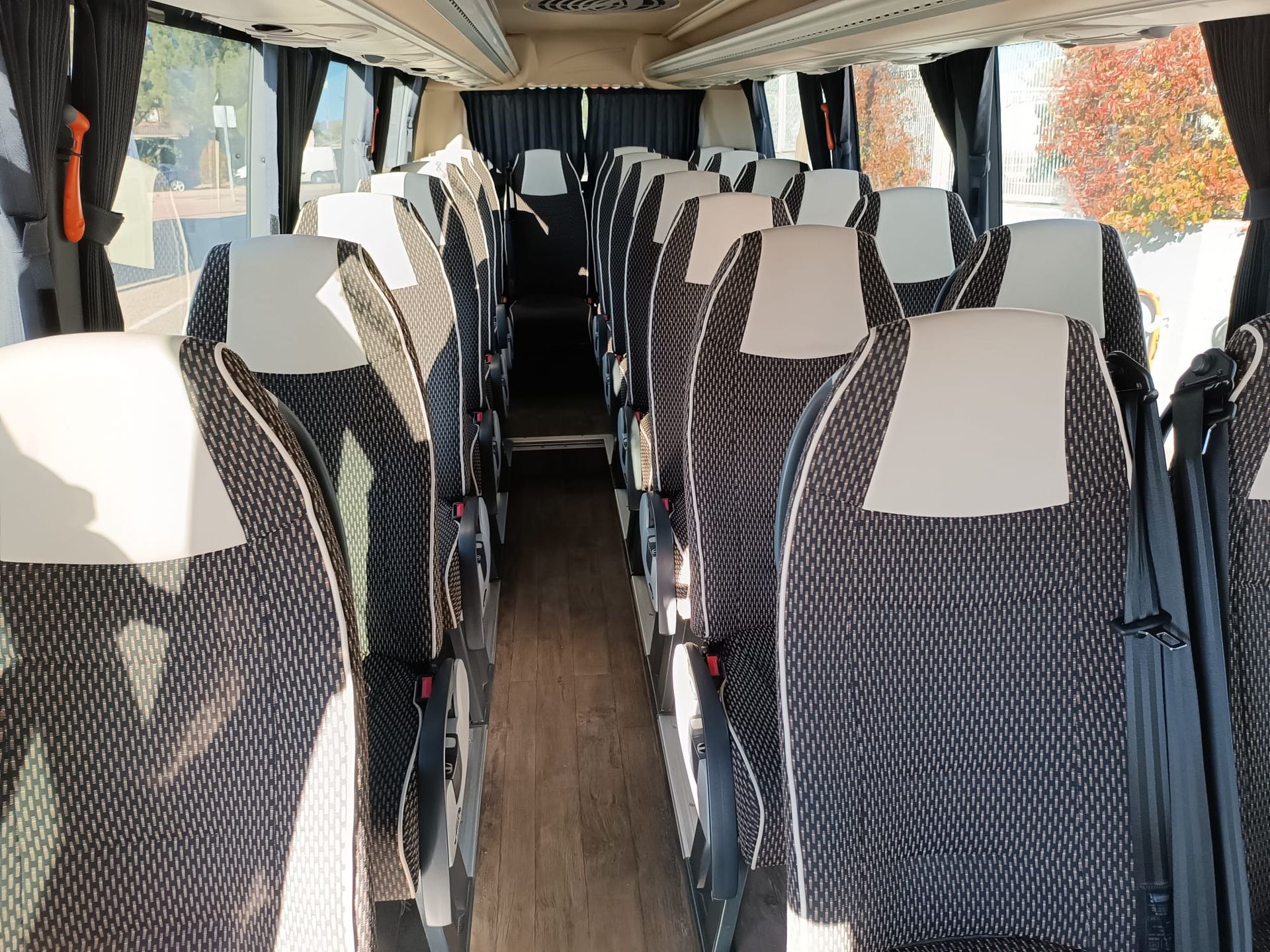 El interior de un autobús con filas de asientos y cortinas.
